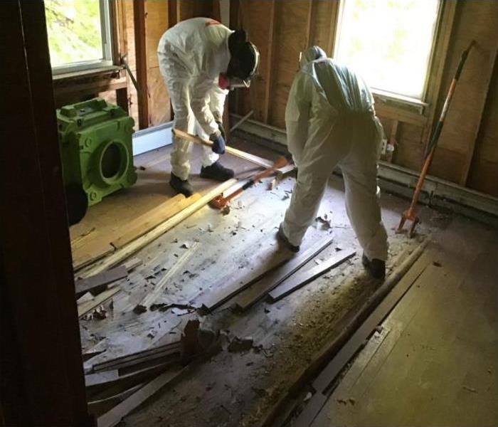 two technicians in room removing floors damaged by water