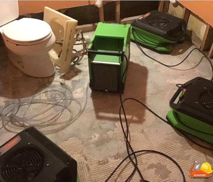 air blowers and dehumidifier placed in bathroom after tiles removed to dry subfloor