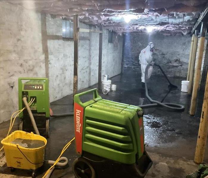 crew member using flood extractor in flooded basement